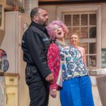 Bailey Patrick as Officer Rogers supports Dame Maureen Lipman as Allegra while Elizabeth Bower as Anna watches from the kitchen.
