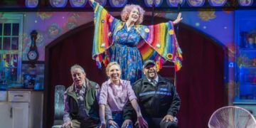 Dame Maureen Lipman as Allegra stands above John Middleton as Ronen, Elizabeth Bower as Anna and Bailey Patrick as Officer Rogers during a colourful musical number.