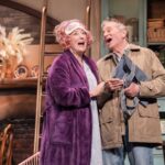 Dame Maureen Lipman as Allegra and John Middleton as Ronen singing together in the cottage kitchen.