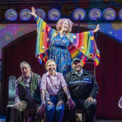 Dame Maureen Lipman as Allegra stands above John Middleton as Ronen, Elizabeth Bower as Anna and Bailey Patrick as Officer Rogers during a colourful musical number.